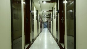 Un largo pasillo bien iluminado con paredes espejadas y piso pulido, que conduce a una entrada distante.