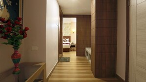 Un pasillo con piso de madera que conduce a un dormitorio con cama y mesita de noche.