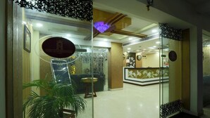Zona de recepción con mostrador, planta en maceta y pared decorativa con un reloj.