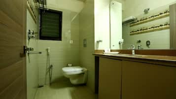 A compact bathroom with a toilet, a shower, and a sink.