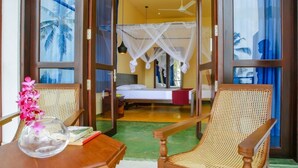 A room with a bed, a chair, a table with a vase, and a window with a view of palm trees. - Sath Villa Naadi Ayurveda Resort (Beruwala)