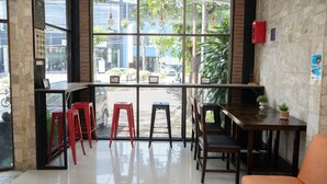 A cafe with a stone wall, large windows, and a wooden table with chairs.