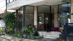 A building with large glass doors, potted plants, and a stone facade.