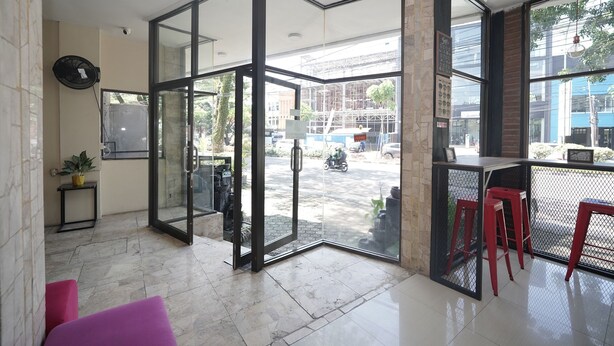 A modern interior with a glass door leading to an outdoor area, a small table with a plant, and red stools.