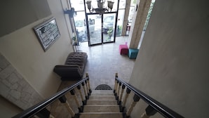 A staircase leading to a lobby with a modern design, including a patterned floor, a framed sign on the wall, and a seating area with a sofa and a chair.