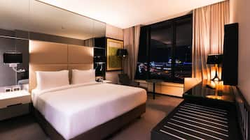 Un hotel moderno con una cama grande, un escritorio, una silla y vistas a la ciudad de noche.