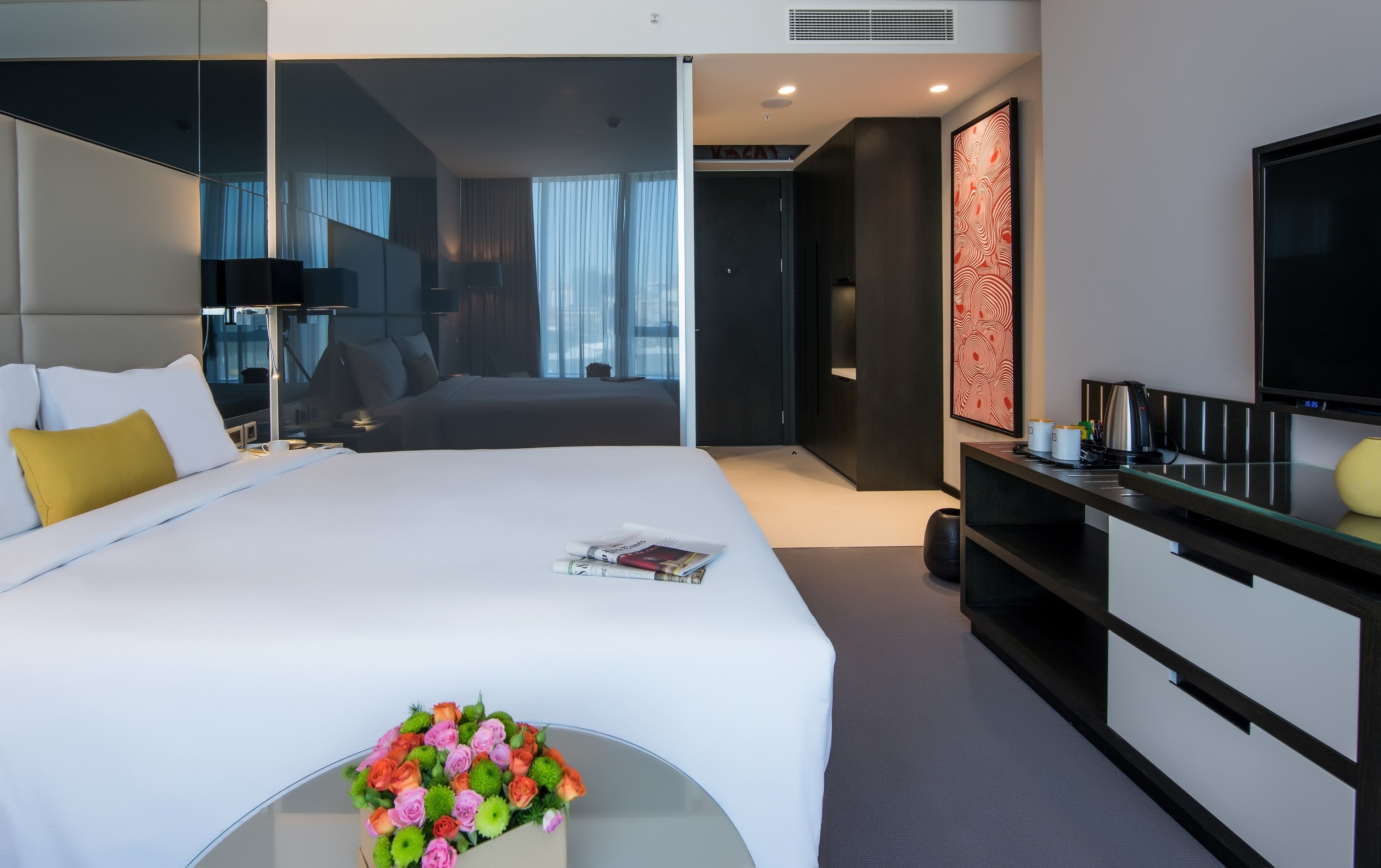 Ett modernt hotellrum med en stor säng, sängbord, en platt-TV och en dekorativ väggdekoration.
