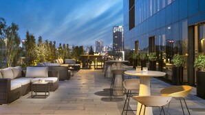 An outdoor seating area with wicker furniture, a round table, and potted plants. - Centro Westside by Rotana (Istanbul)
