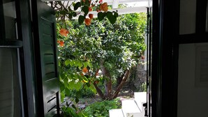 Une porte ouverte donnant sur un jardin où se trouvent un banc et un sentier.