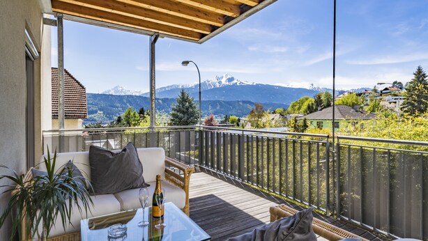 A balcony with a glass table, wicker furniture, and a view of mountains. - Design Apartments mit Terrasse - Adults Only (Innsbruck)
