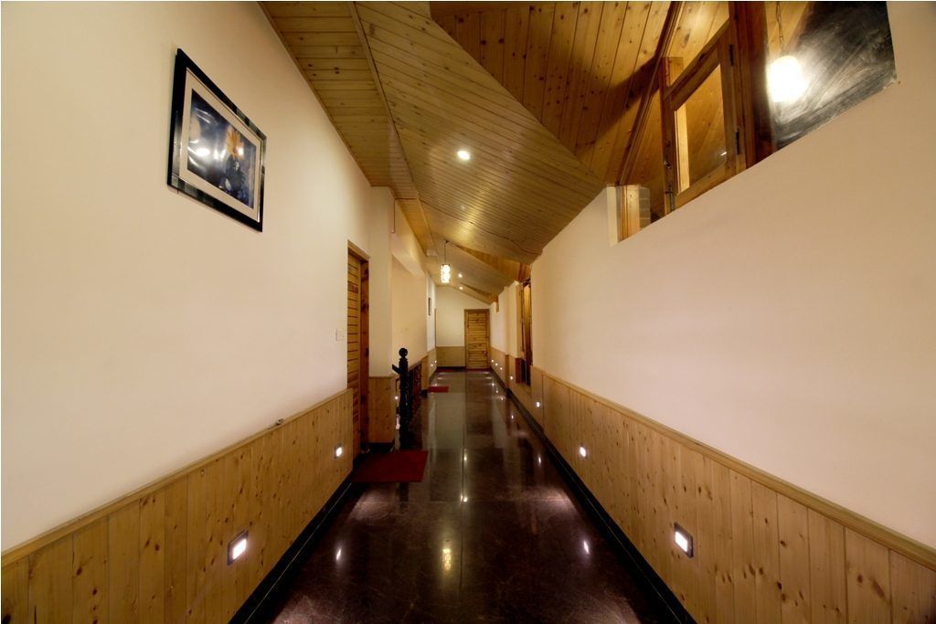 A long, narrow hallway with wooden paneling on the walls and ceiling, recessed lighting, and a framed picture on the left wall.