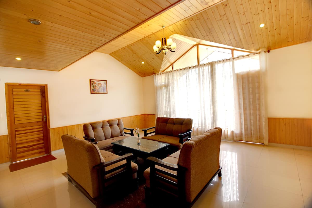 A spacious living room with a high ceiling, wooden walls, and a large window with curtains.