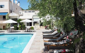 Una piscina al aire libre, sombrillas, tumbonas