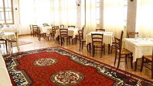 A dining area with multiple tables and chairs, arranged in a spacious room with large windows and a patterned carpet. - Aquam Albergo (Acqui Terme)