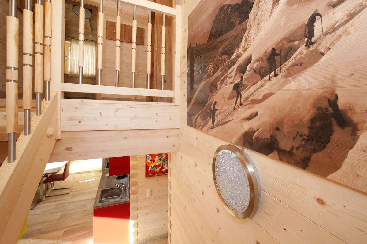 A wooden interior with a kitchen area, a dining table, and a painting of a mountainous landscape.