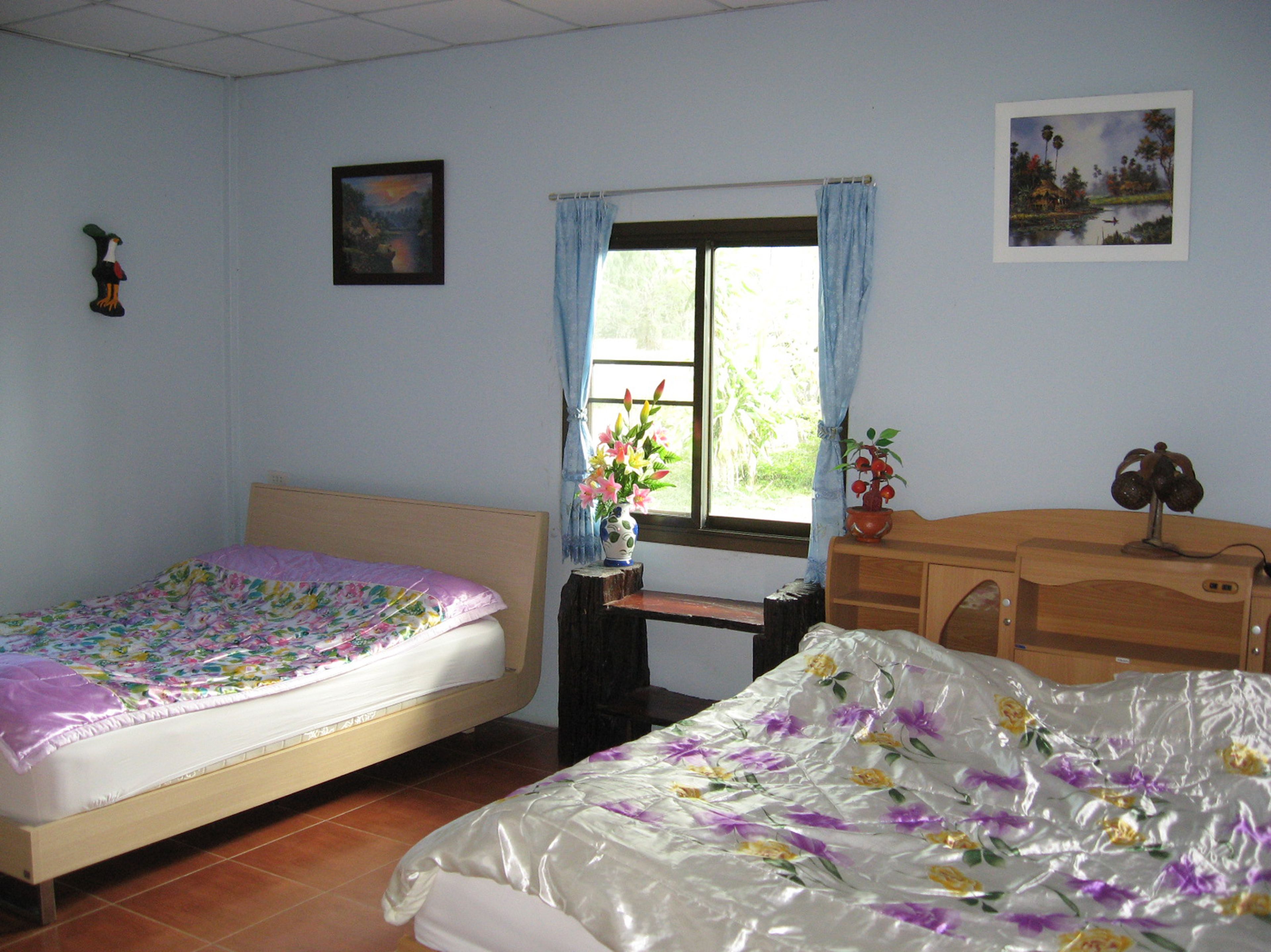 Un dormitorio con dos camas, una ventana con cortinas, un escritorio y un aparador.