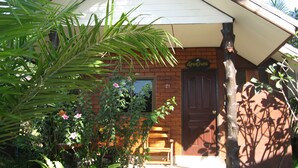 Una casa de ladrillo con un porche blanco, un banco de madera y una puerta marcada con el número 21.
