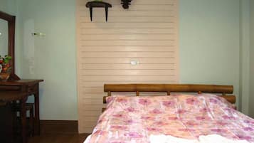 Une chambre à coucher avec un lit en bois, une table de chevet ornée d’un vase de fleurs et une lampe fixée au mur.