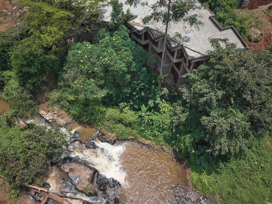 A traditional building with a unique architectural style, surrounded by lush greenery and a flowing stream.