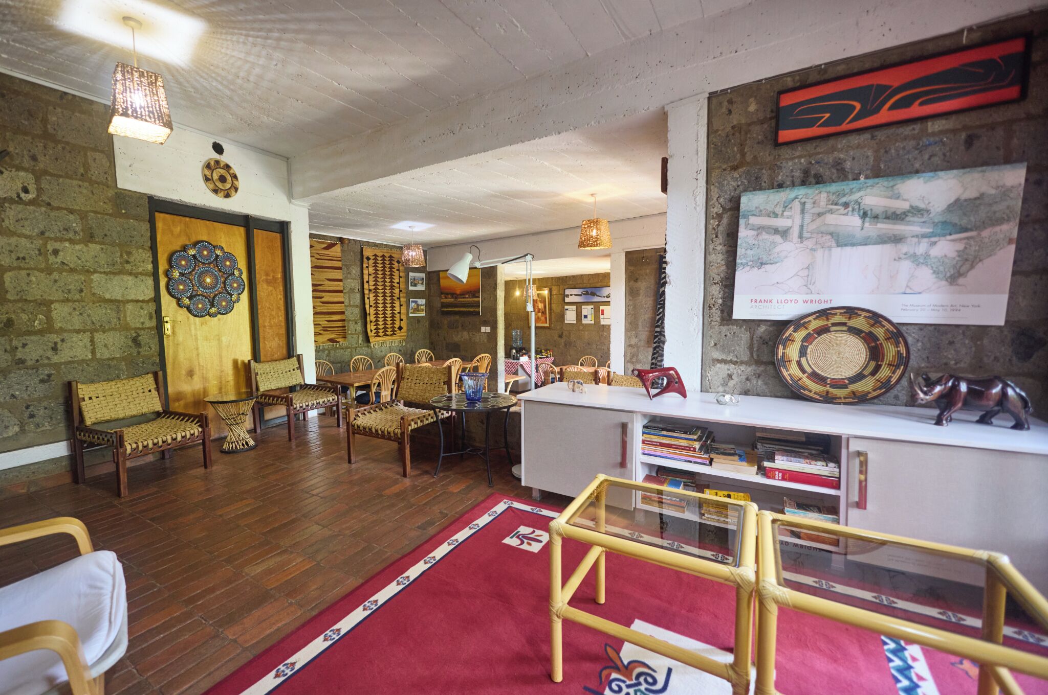 A room with a wooden floor, wicker furniture, a red carpet, a white desk, and a wall-mounted picture.
