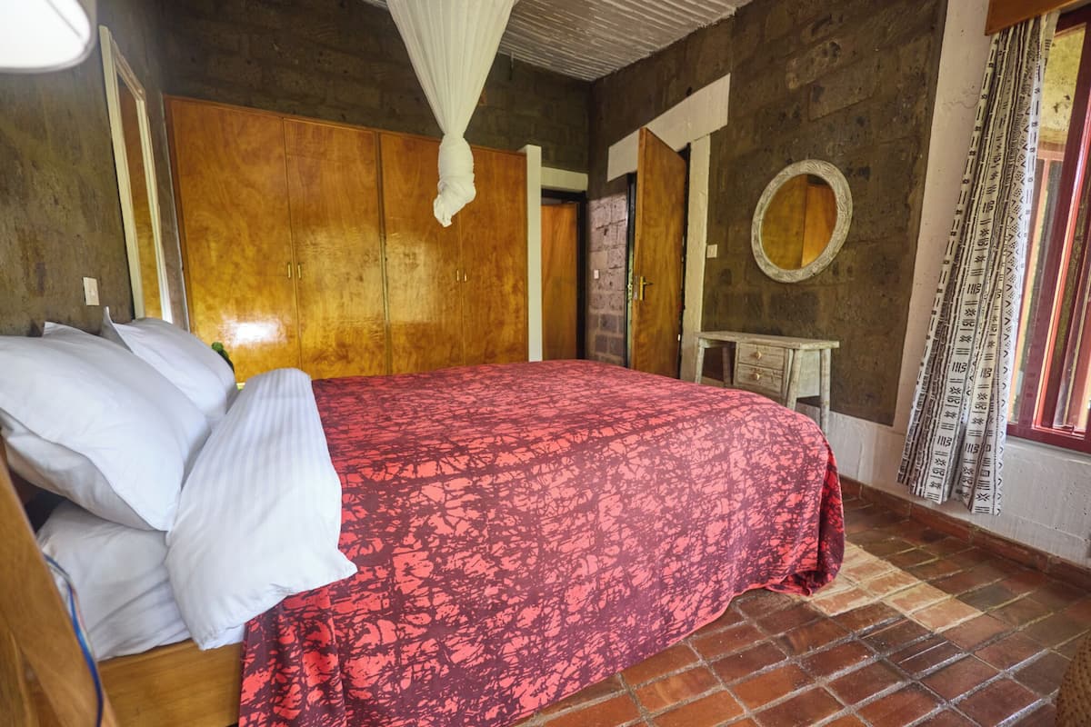 A room with a bed, wooden wardrobe, and a small table.
