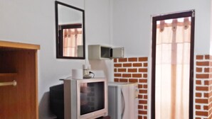 Un ambiente compatto con televisione, frigorifero e un tavolino con cestino.