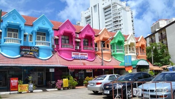 Una fila di case colorate con insegne che riportano 'Devils Divers' e 'Sweet House Guest House'.