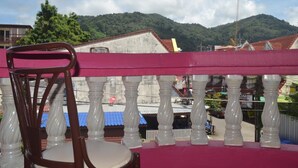 Un balcone con una sedia, una ringhiera e vista su una montagna e edifici sullo sfondo.
