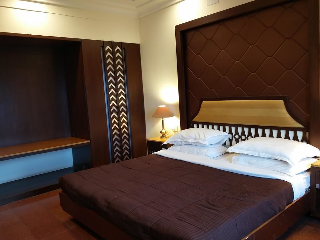 A hotel room with a large bed, a TV, and a nightstand with a lamp.