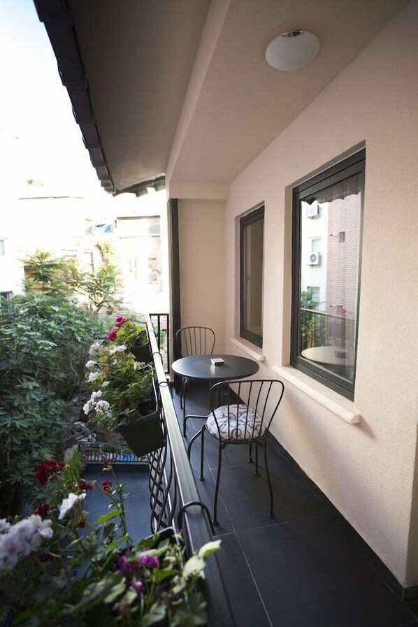 Ein Balkon mit einem kleinen Tisch und Stühlen, umgeben von Blumentöpfen und Blumen.