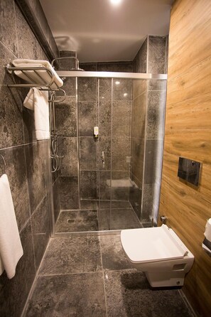 Ein modernes Badezimmer mit einer Duschkabine, einer weißen Toilette und einem Handtuchhalter.