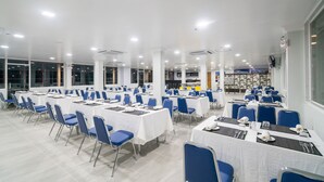 A large, well-lit conference room with rows of tables and chairs, equipped with nameplates and table settings. - Sakura Hotel (Yangon)