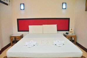 A hotel room with a large bed, two bedside tables, and a red headboard.