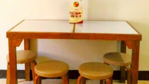 A small wooden table with four stools, a whiteboard on the wall above, and a box of snacks on the table. - Asiatel Hotel, Sta. Rosa, Laguna (Santa Rosa)