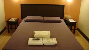 A hotel room with a large bed, two nightstands, a headboard, and two wall-mounted lights. - Asiatel Hotel, Sta. Rosa, Laguna (Santa Rosa)