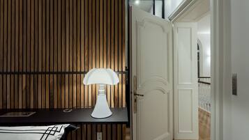 Een moderne kamer met een wand van houten latten, een witte deur en een tafel met een lamp.