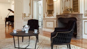 A grand room with a piano, a fireplace, and two chairs with a table set for tea. - Villa Camoufle (Metz)