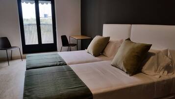 Una camera d'albergo con un letto, due sedie, un tavolino e un balcone con ringhiera.