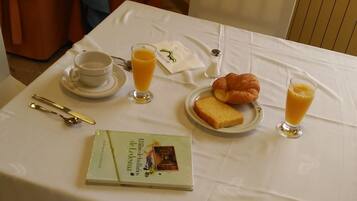 Una mesa de desayuno con un croissant, dos vasos de zumo de naranja, una taza de té y un libro titulado
