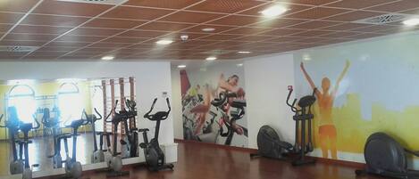 A gym with various exercise equipment, including treadmills and stationary bikes, and motivational wall art.
