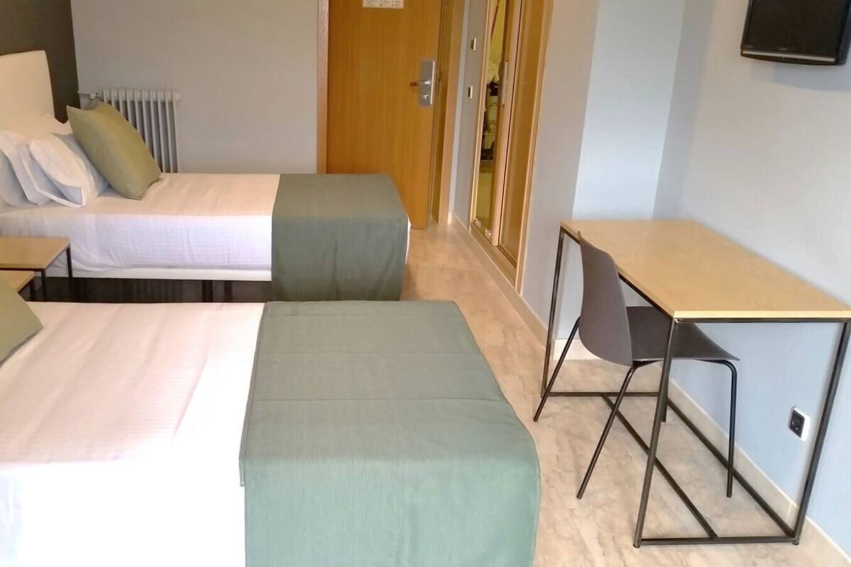 Een hotelkamer met twee bedden, een bureau en een stoel.