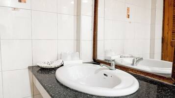 Un baño con lavamanos blanco, un espejo y una bañera.