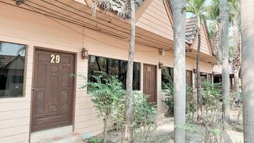 A building with numbered doors, likely a hotel or guesthouse, with a tiled roof and palm trees in the vicinity.