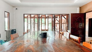 A spacious room with a large wooden table, chairs, and a view through a wooden lattice door. - The Northern View Hotel (Sung Men)