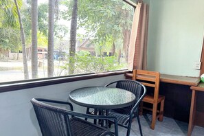 A small round table with four wicker chairs, a window with curtains, and a view of trees and buildings outside. - The Northern View Hotel (Sung Men)