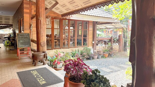 A wooden building with a tiled ceiling, a welcome mat, and potted plants. - The Northern View Hotel (Sung Men)