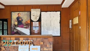 A reception desk with a 'WELCOME' sign, a framed portrait, and a directional sign. - The Northern View Hotel (Sung Men)