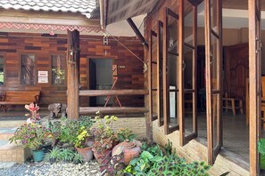 A wooden building with a porch, potted plants, and a bench. - The Northern View Hotel (Sung Men)