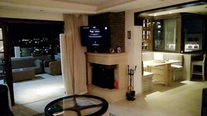 A modern living room with a fireplace, a television, and a dining area. - Yamsafer Homes 4th Circle (Amman)