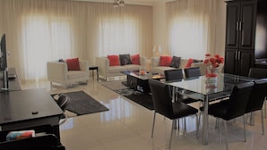A modern living room with a sofa set, a glass coffee table, and a dining table with chairs. - Yamsafer Homes 4th Circle (Amman)